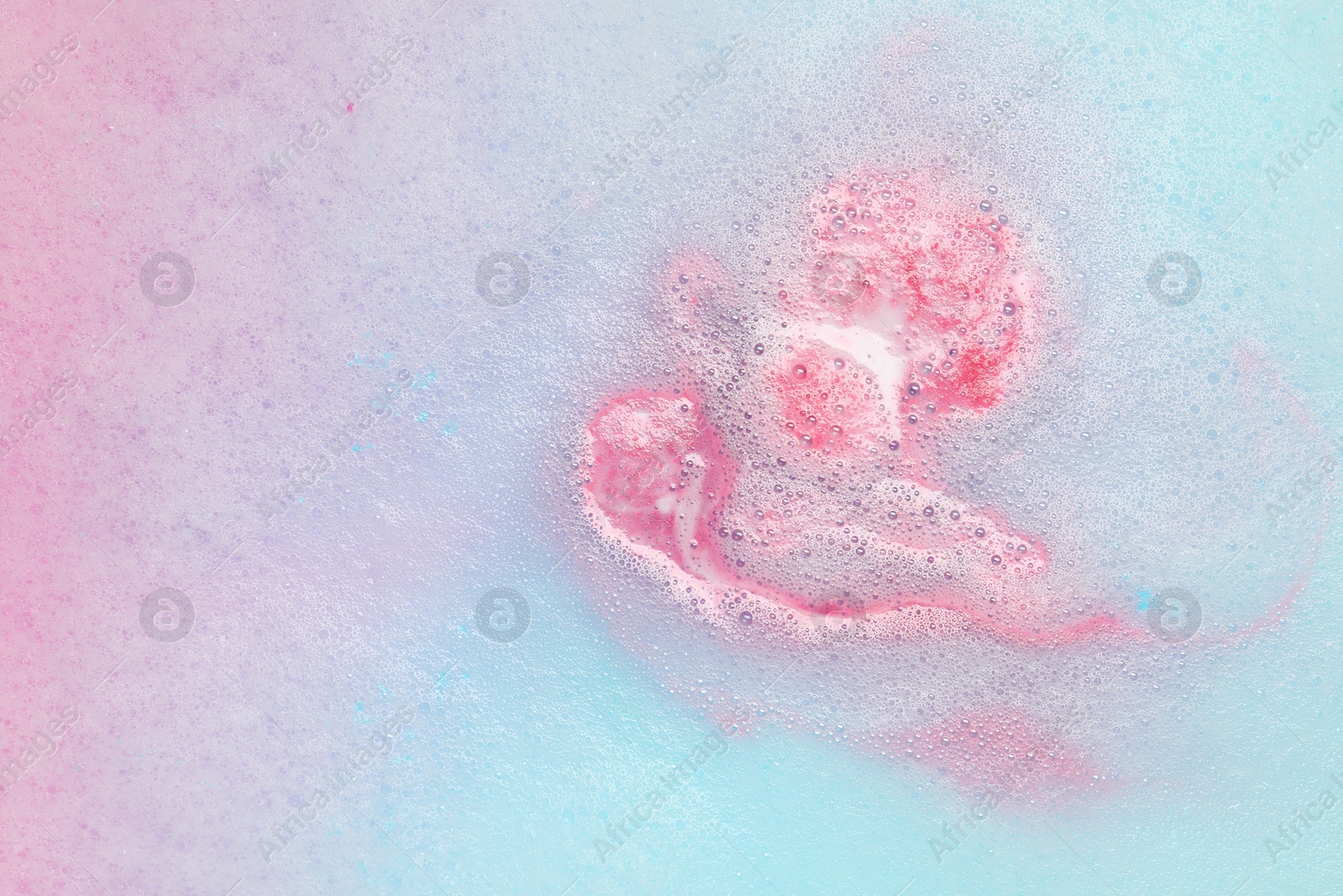 Photo of Colorful foam after dissolving bath bomb in water, closeup