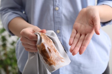 Photo of Woman showing stain from coffee on jacket against blurred background, closeup