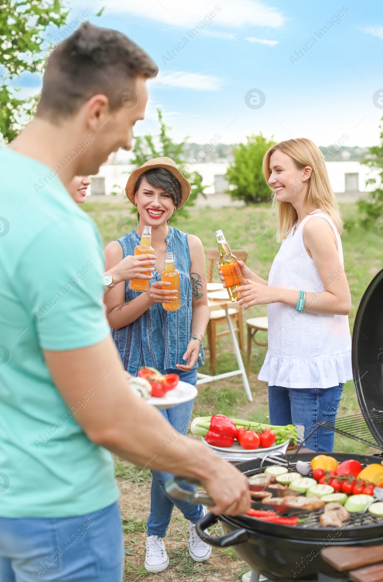 Photo of Young people having barbecue with modern grill outdoors