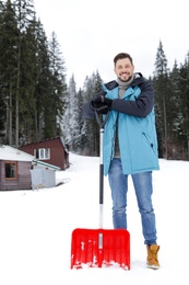 Man with shovel for snow removal near house