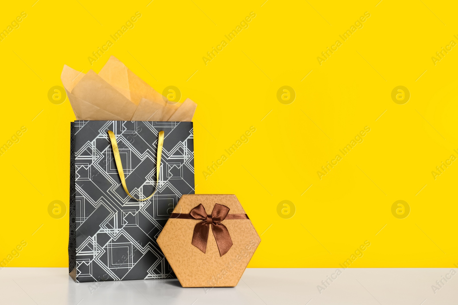 Photo of Shopping bag and gift box on yellow background. Space for text