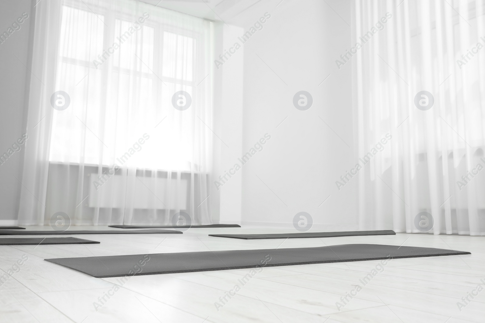 Photo of Spacious yoga studio with exercise mats, low angle view