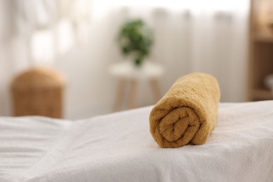 Rolled towel on massage table in spa center, closeup. Space for text