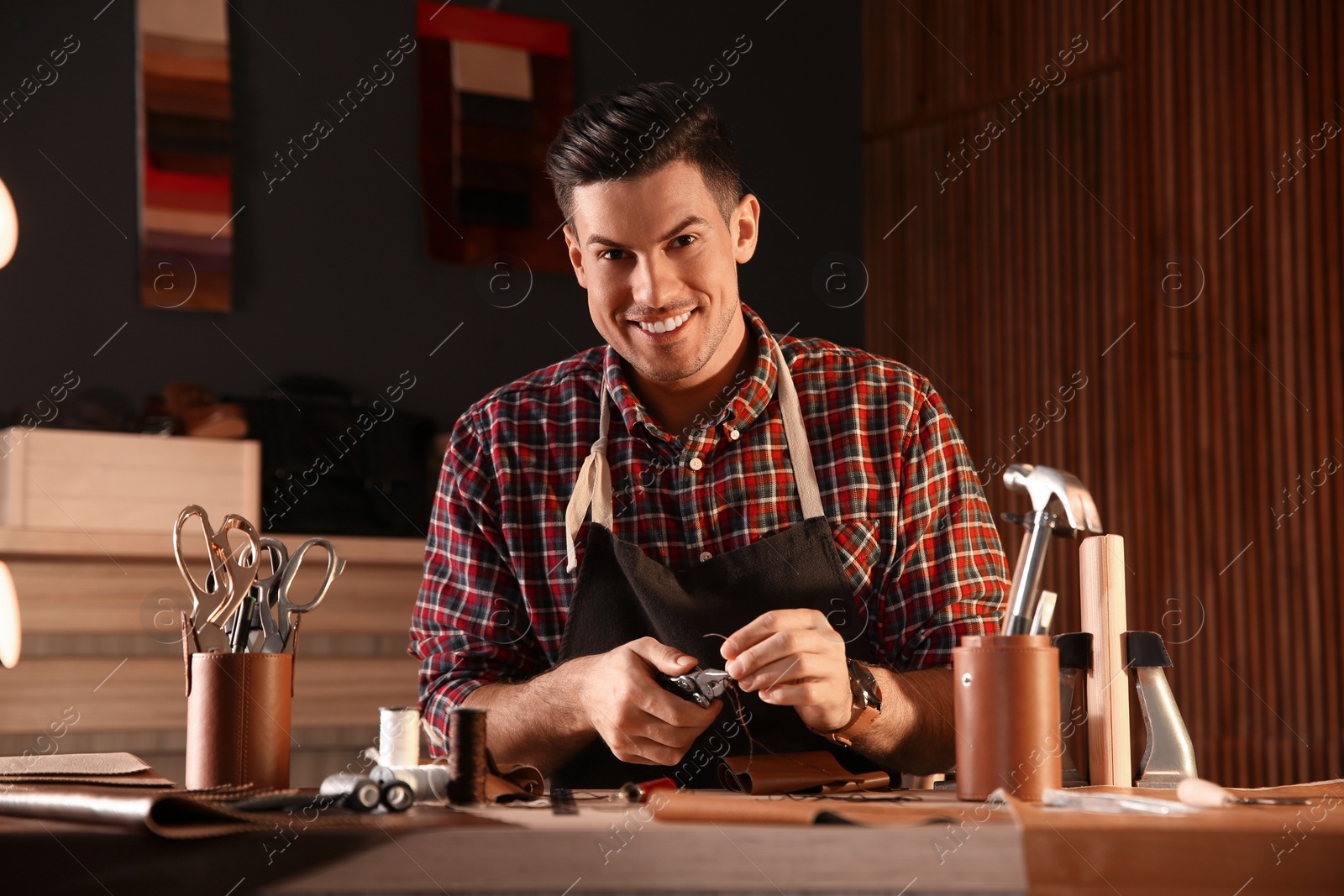 Photo of Man sewing piece of leather in workshop