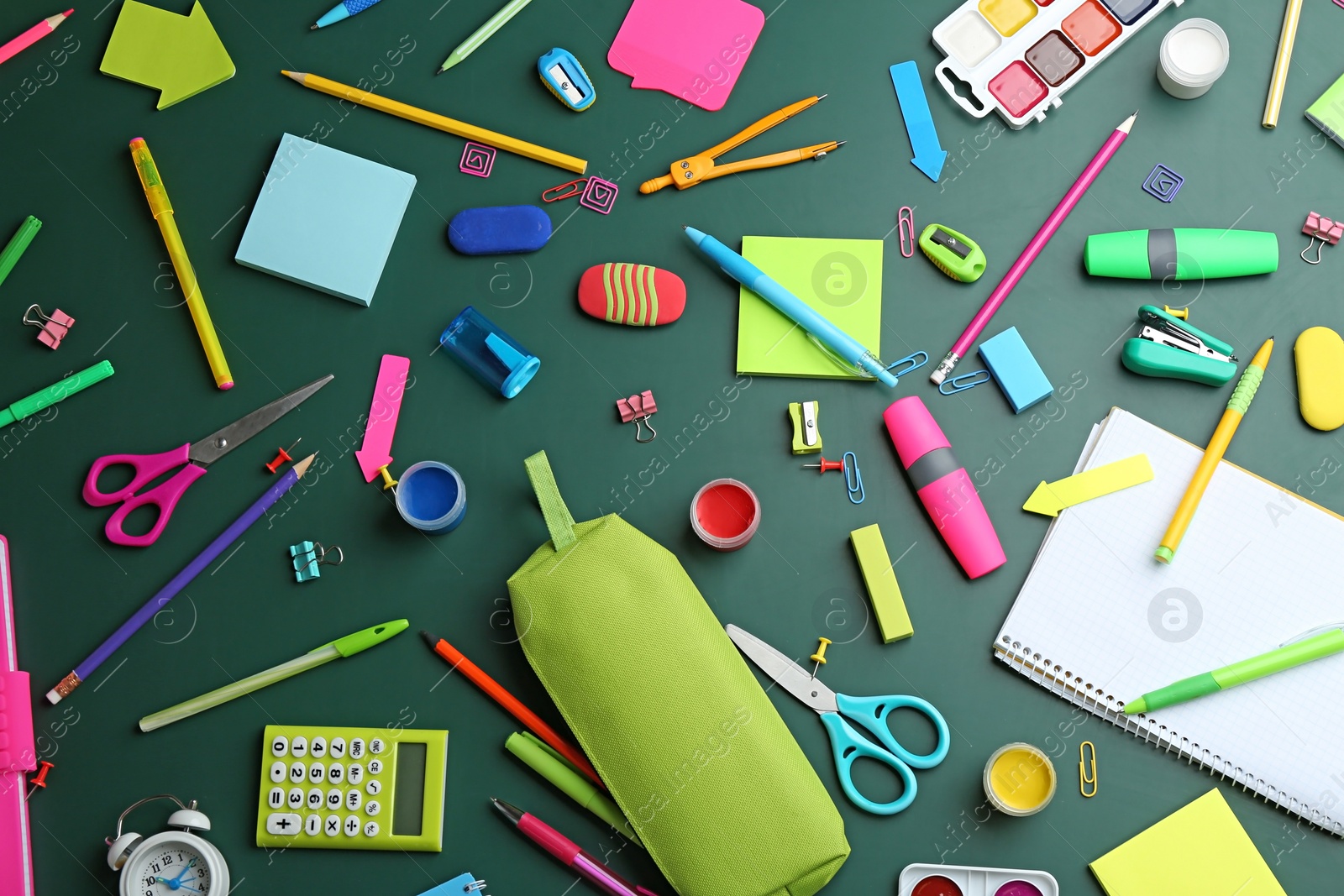 Photo of Different bright school stationery on green background, flat lay