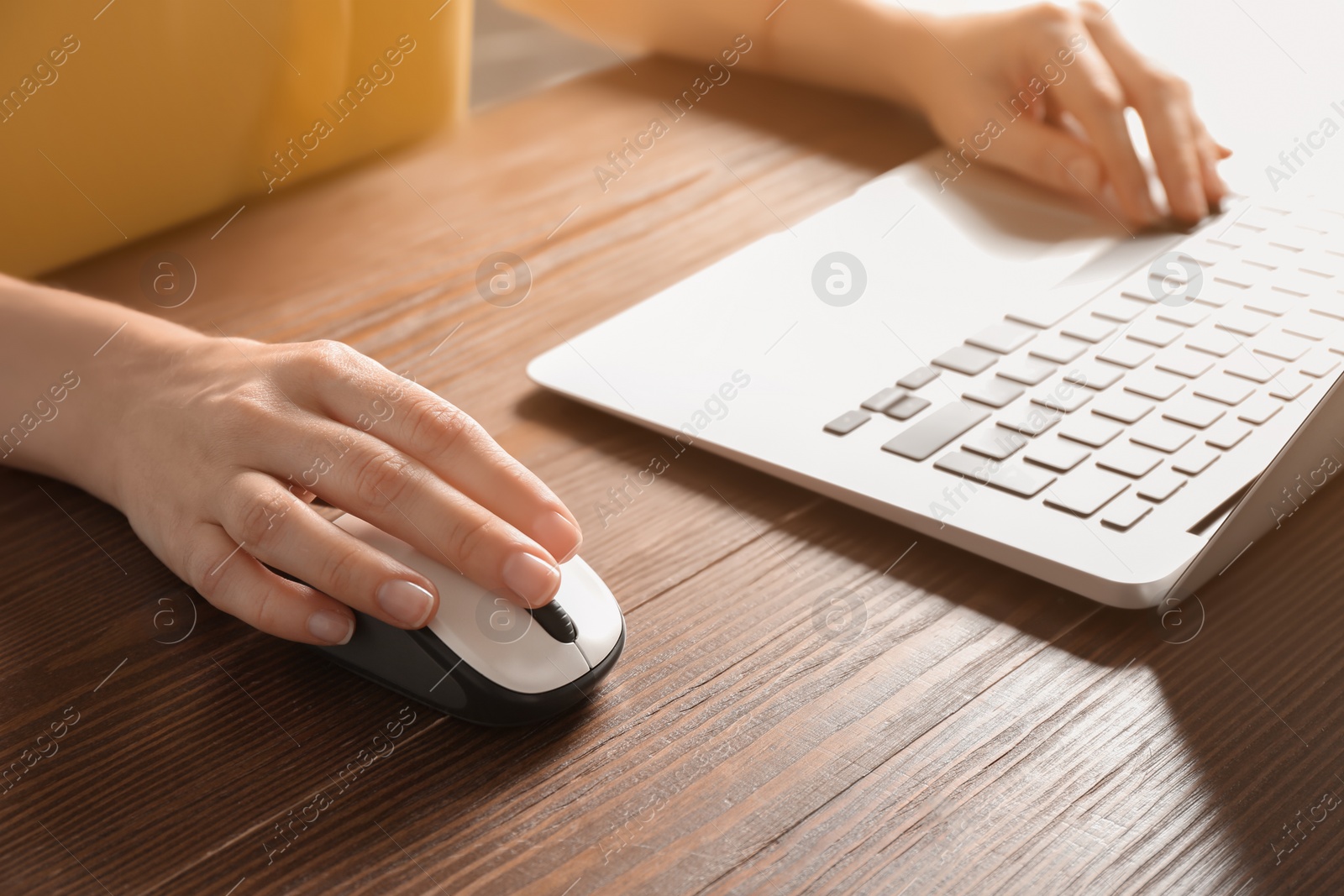 Photo of Woman using computer mouse with laptop at table, closeup