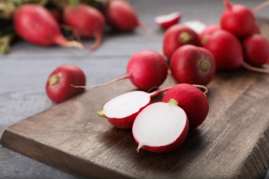 Photo of Fresh ripe radishes on grey wooden table, closeup. Space for text