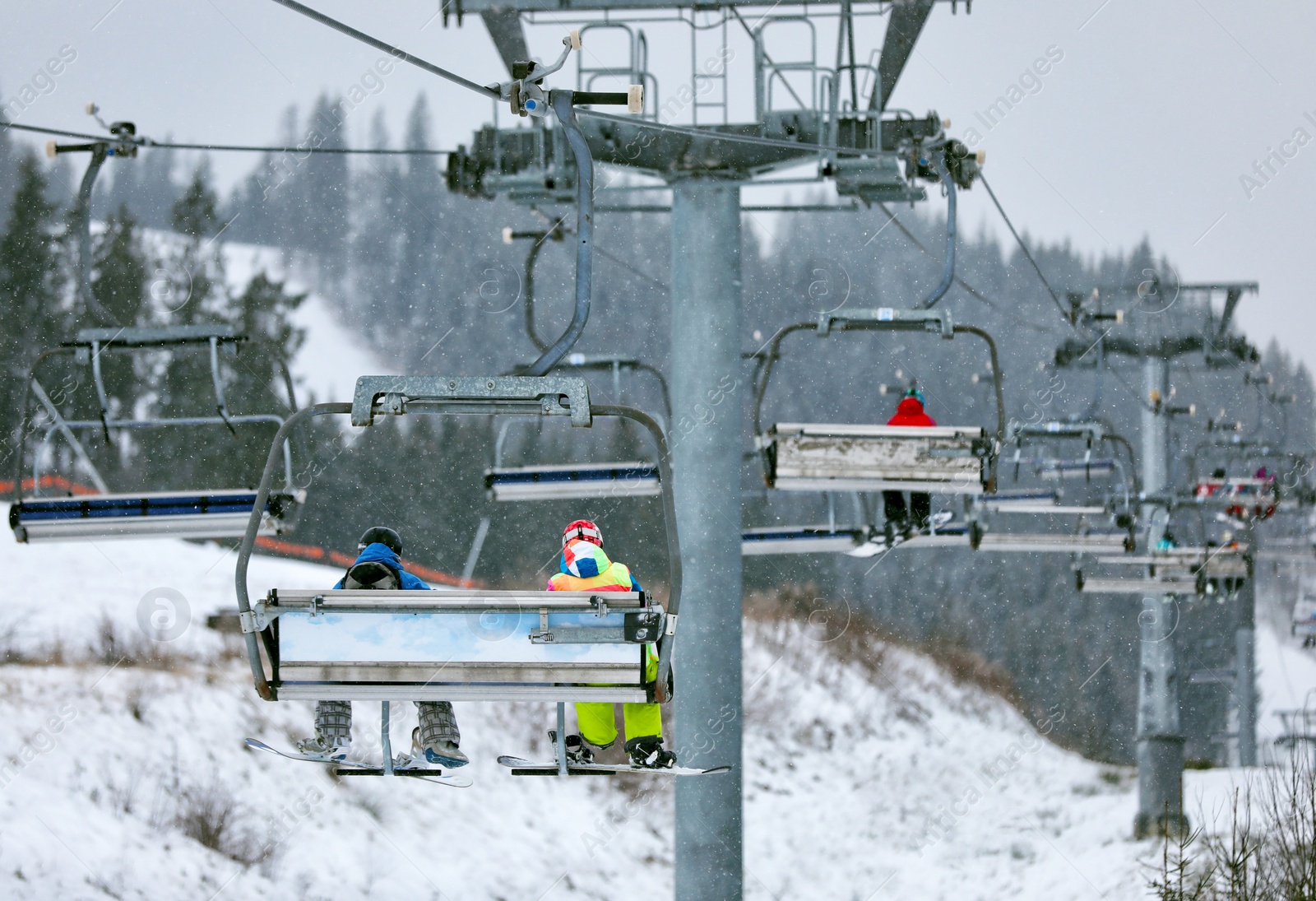 Photo of Chairlift with people at ski resort. Winter vacation