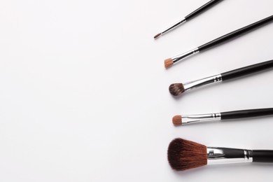 Photo of Set of makeup brushes on white background, flat lay. Space for text