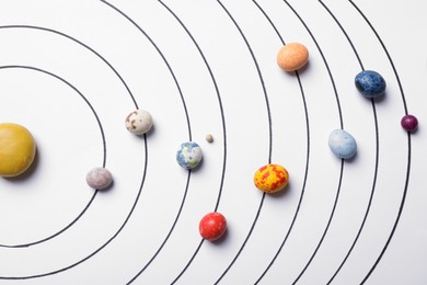 Photo of Flat lay composition with colorful stones on white background representing solar system