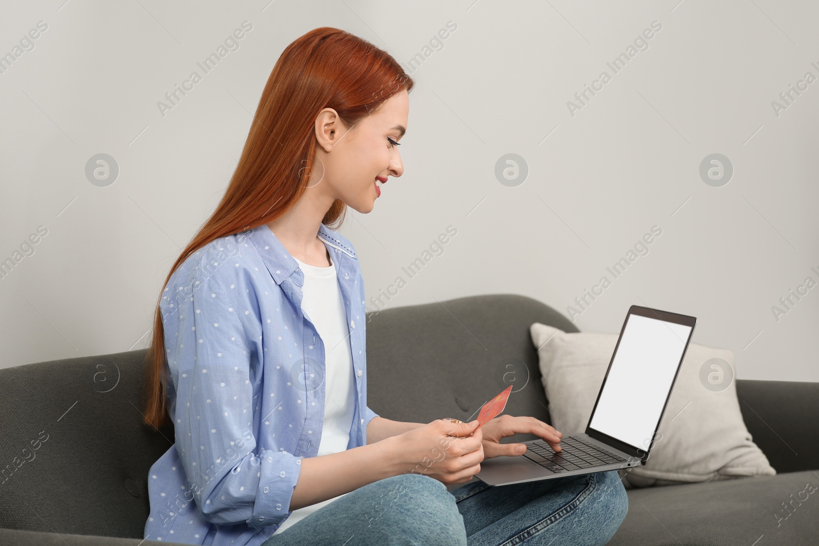 Photo of Happy woman with credit card using laptop for online shopping on sofa at home. Space for text