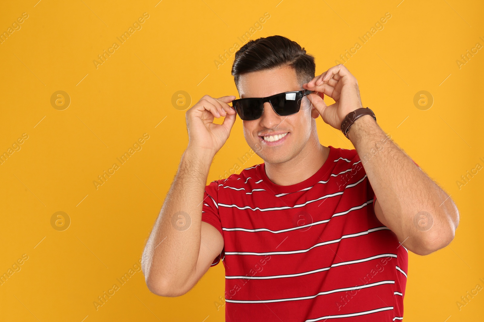 Photo of Handsome man wearing sunglasses on yellow background