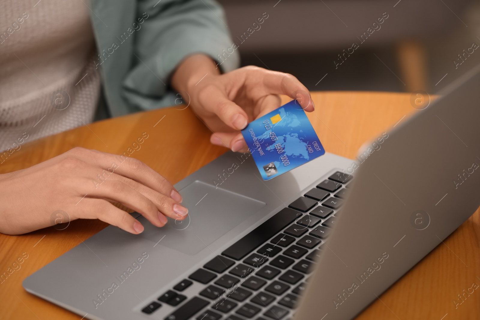 Photo of Woman with credit card using laptop for online shopping at wooden table, closeup