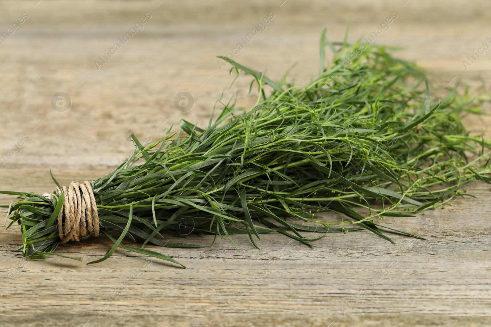Photo of Bunch of fresh tarragon on wooden table, closeup