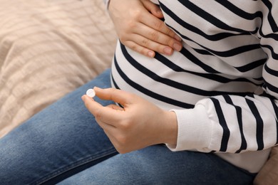 Photo of Pregnant woman with pill at home, closeup
