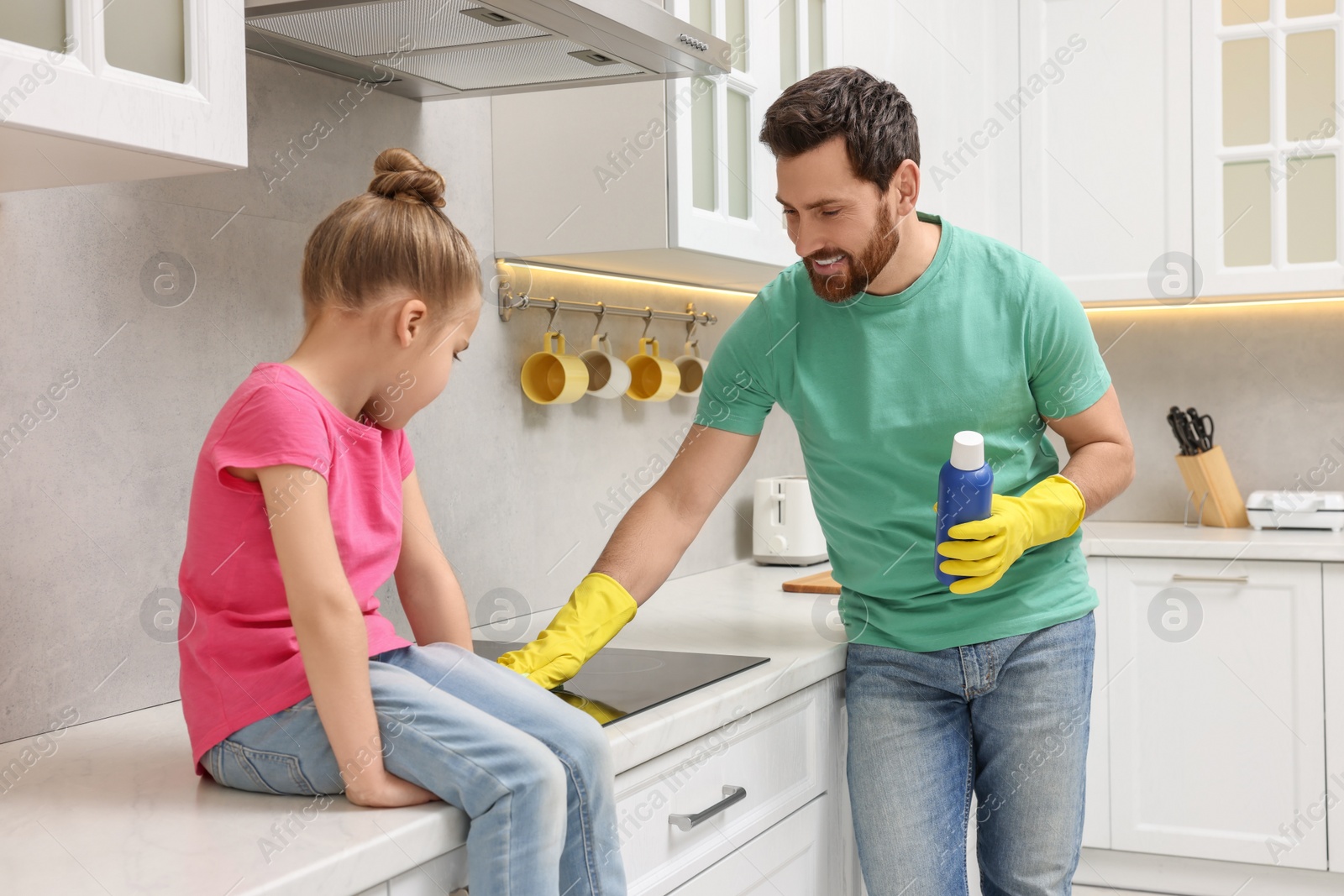 Photo of Spring cleaning. Father and daughter tidying up stove in kitchen together