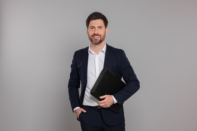 Photo of Happy real estate agent with leather portfolio on grey background