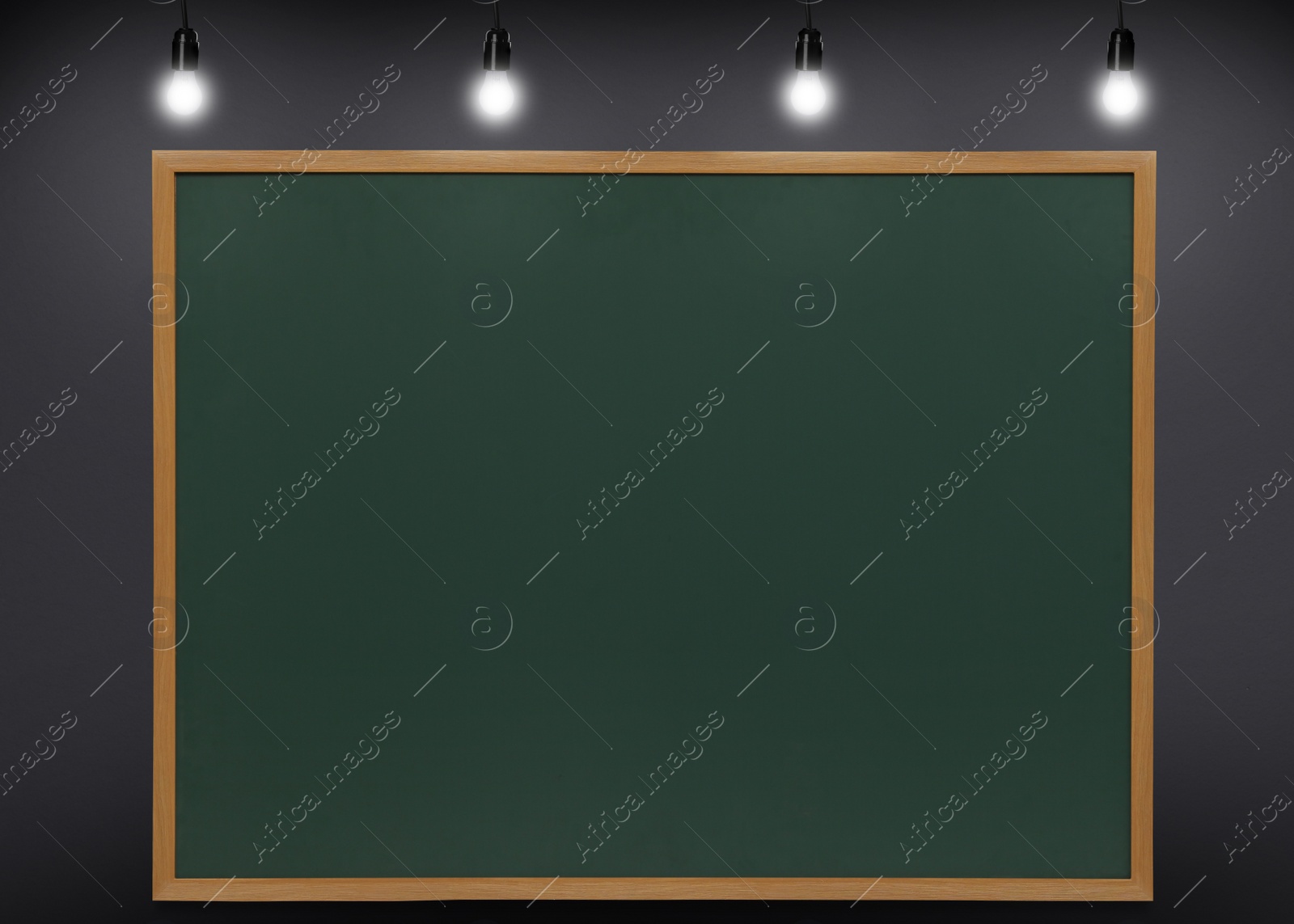 Image of Glowing light bulbs and green chalkboard hanging on grey wall