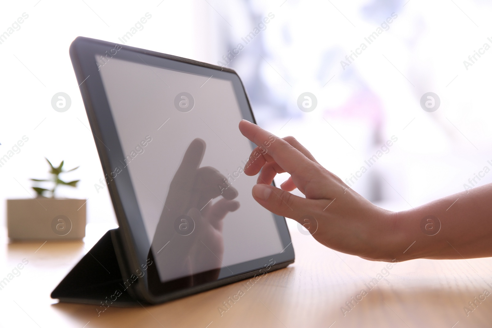 Photo of Woman working with modern tablet at wooden table, closeup