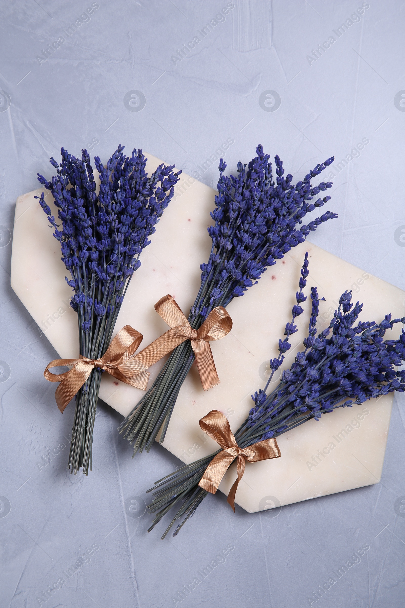 Photo of Bouquets of beautiful preserved lavender flowers and stone board on light grey textured table, top view