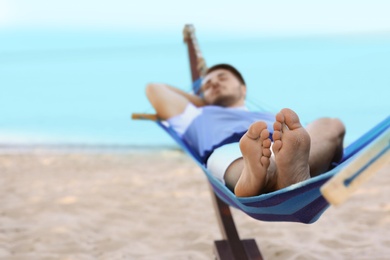 Young man lying in hammock at seaside. Summer vacation