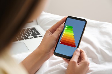 Image of Energy efficiency. Woman using smartphone with colorful rating on display, closeup