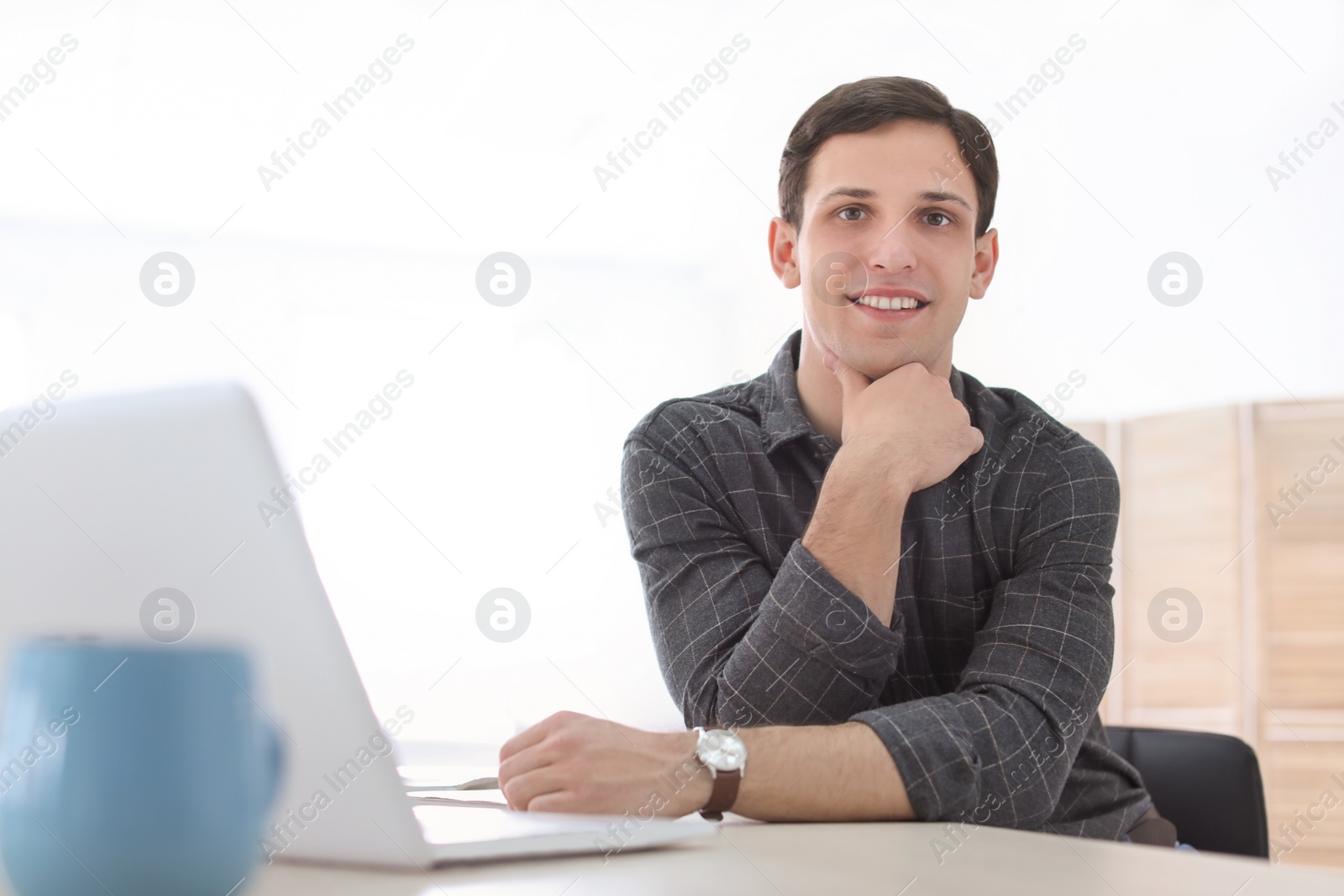 Photo of Portrait of confident young man with  laptop at table