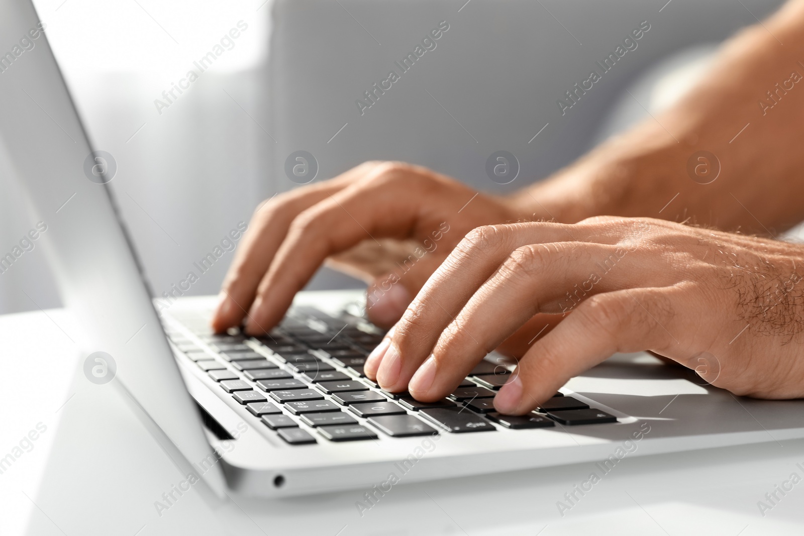 Photo of Man using laptop for search at white table indoors, closeup