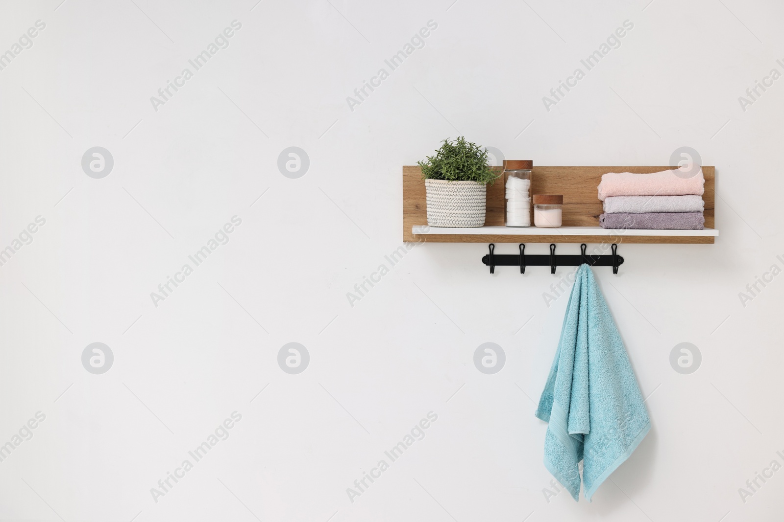 Photo of Clean towels, houseplant and toiletries on shelf indoors. Space for text