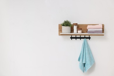 Photo of Clean towels, houseplant and toiletries on shelf indoors. Space for text