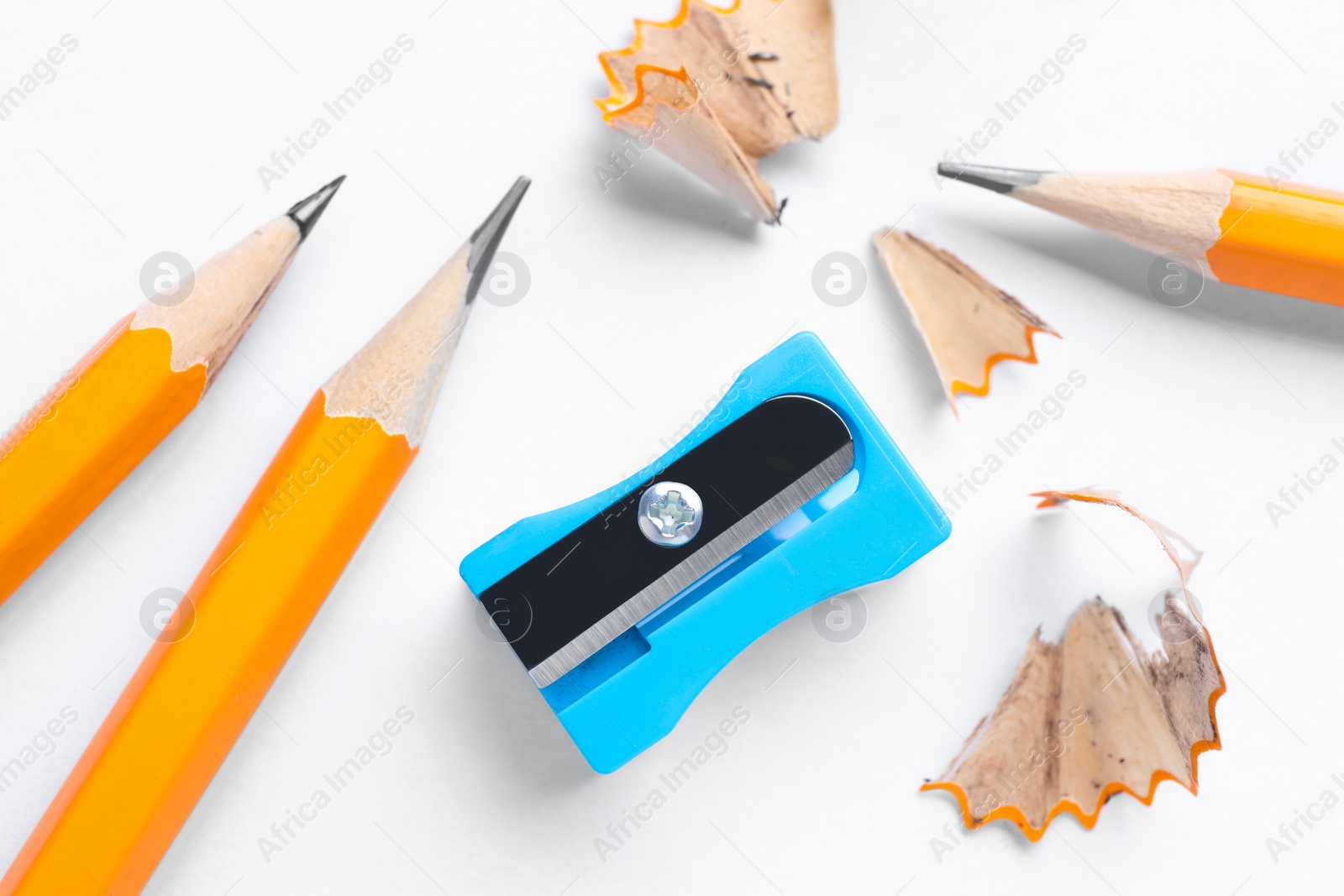 Photo of Pencils, sharpener and shavings on white background, flat lay