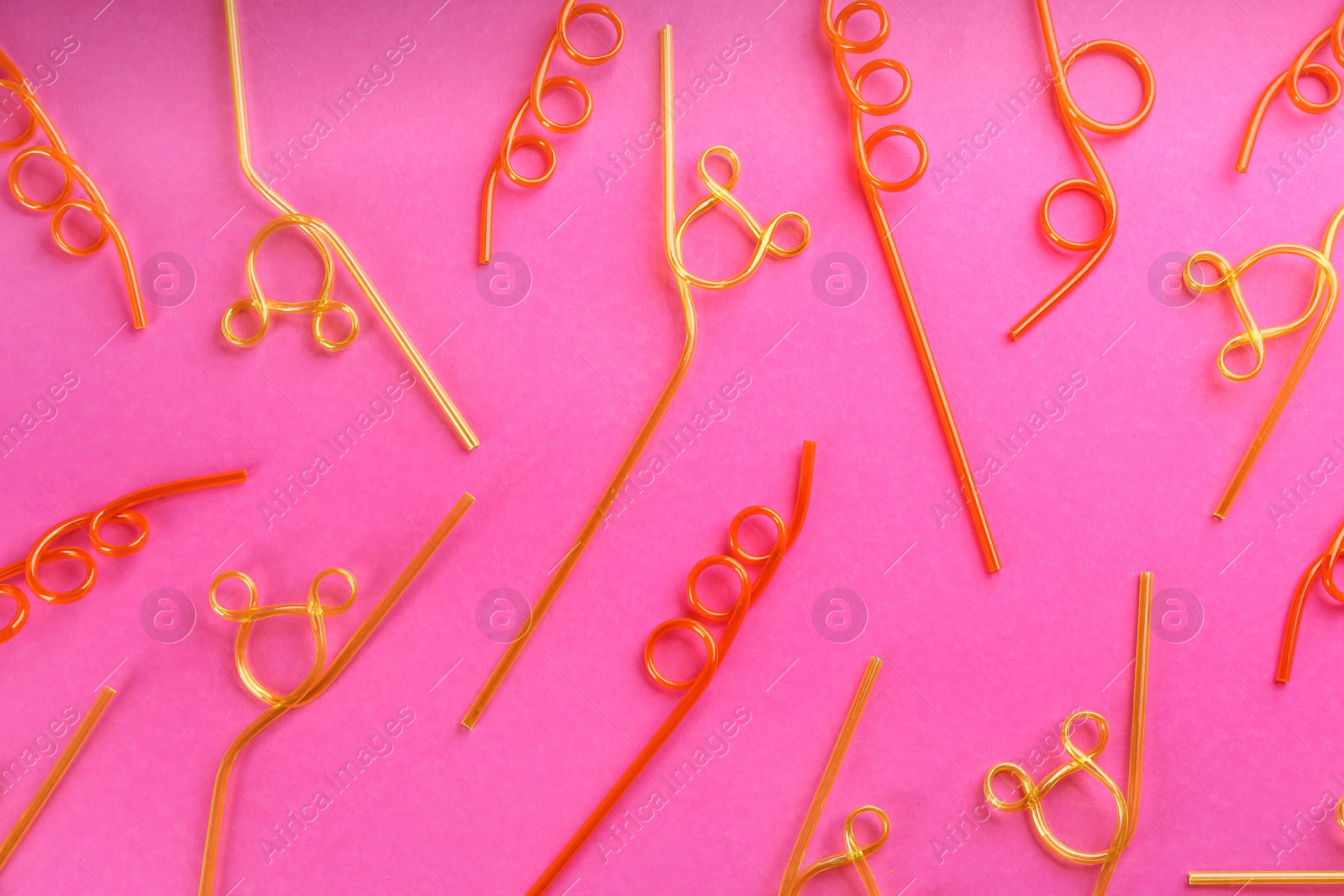 Photo of Colorful plastic drinking straws on pink background, flat lay