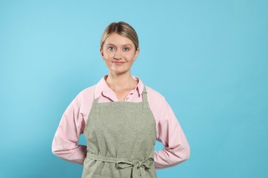 Photo of Beautiful young woman in clean apron with pattern on light blue background