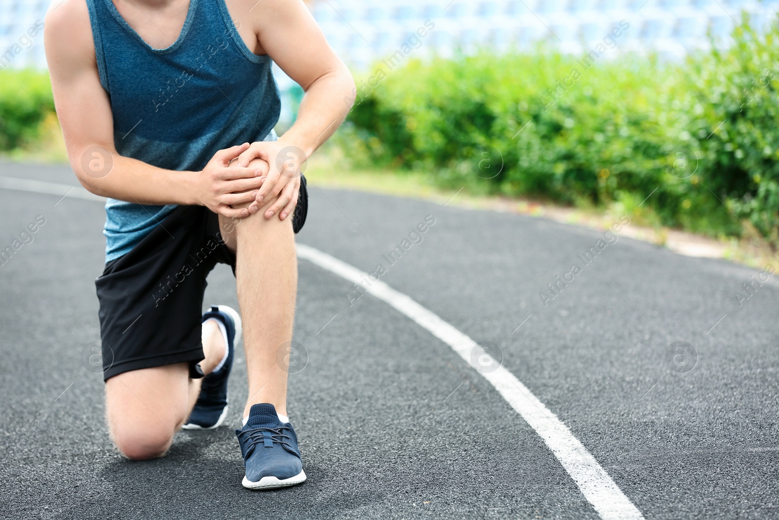 Photo of Man in sportswear suffering from knee pain at stadium, closeup