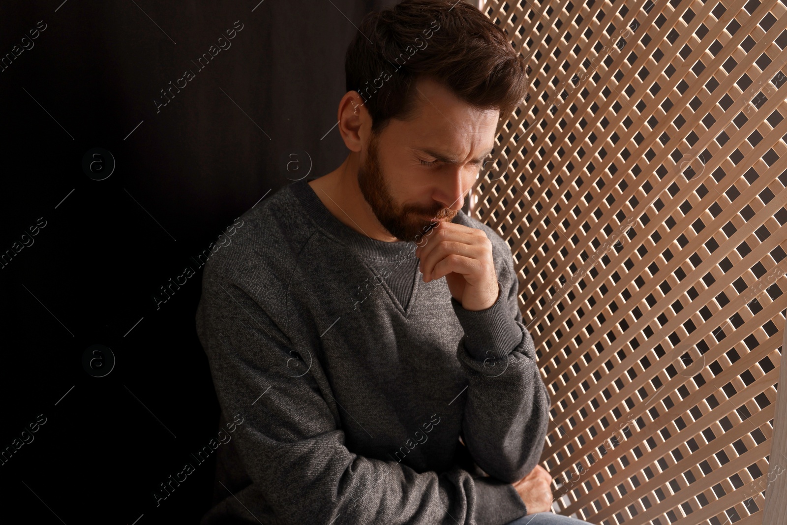 Photo of Upset man listening to priest during confession in booth