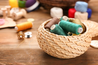 Photo of Small box with set of color sewing threads on wooden background