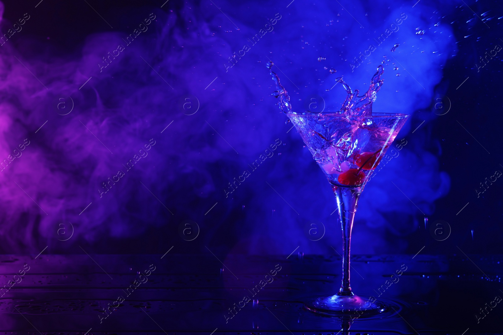 Photo of Martini splashing out of glass in neon lights, space for text