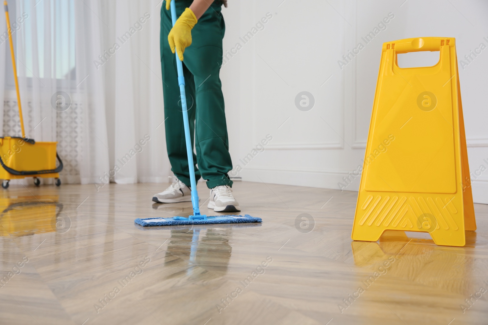 Photo of Professional janitor cleaning parquet floor with mop indoors, closeup