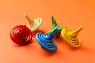 Many colorful spinning tops on orange background, closeup