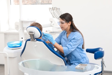 Photo of Professional dentist working with little boy in clinic