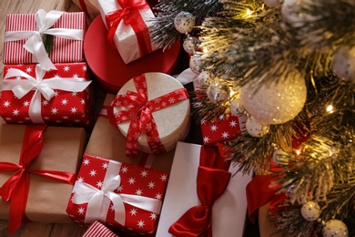 Photo of Pile of gift boxes near beautiful Christmas tree indoors, above view