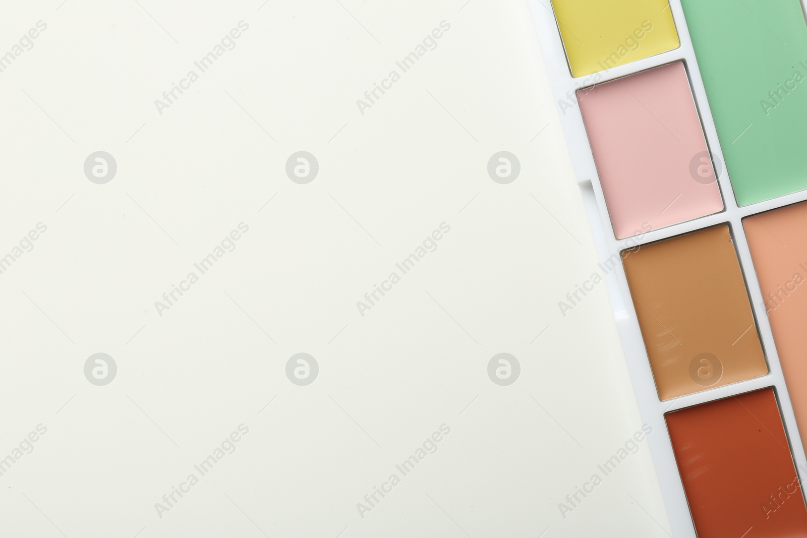 Photo of Colorful correcting concealer palette on white background, top view