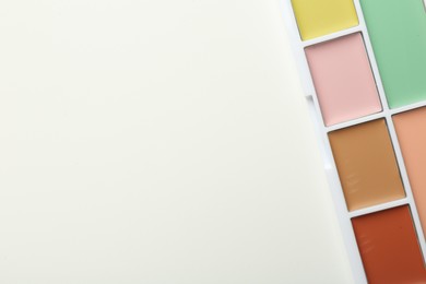 Photo of Colorful correcting concealer palette on white background, top view