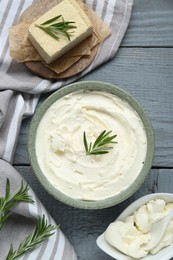 Photo of Delicious tofu cheese with rosemary on grey wooden table, flat lay