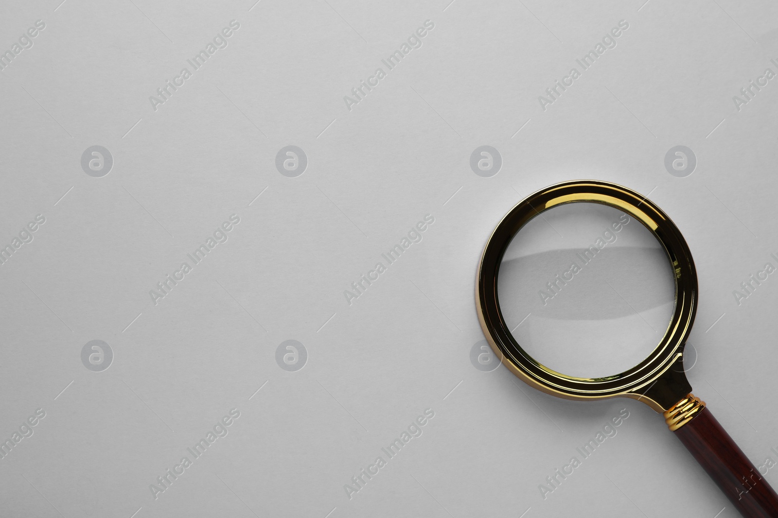 Photo of Magnifying glass on light grey background, top view. Space for text
