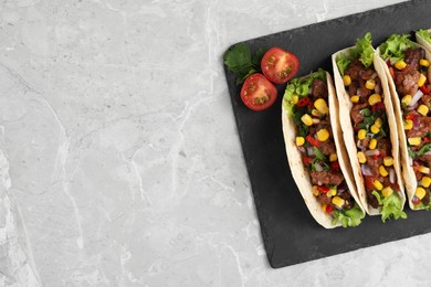 Photo of Delicious tacos with meat and vegetables on light gray marble table, top view. Space for text