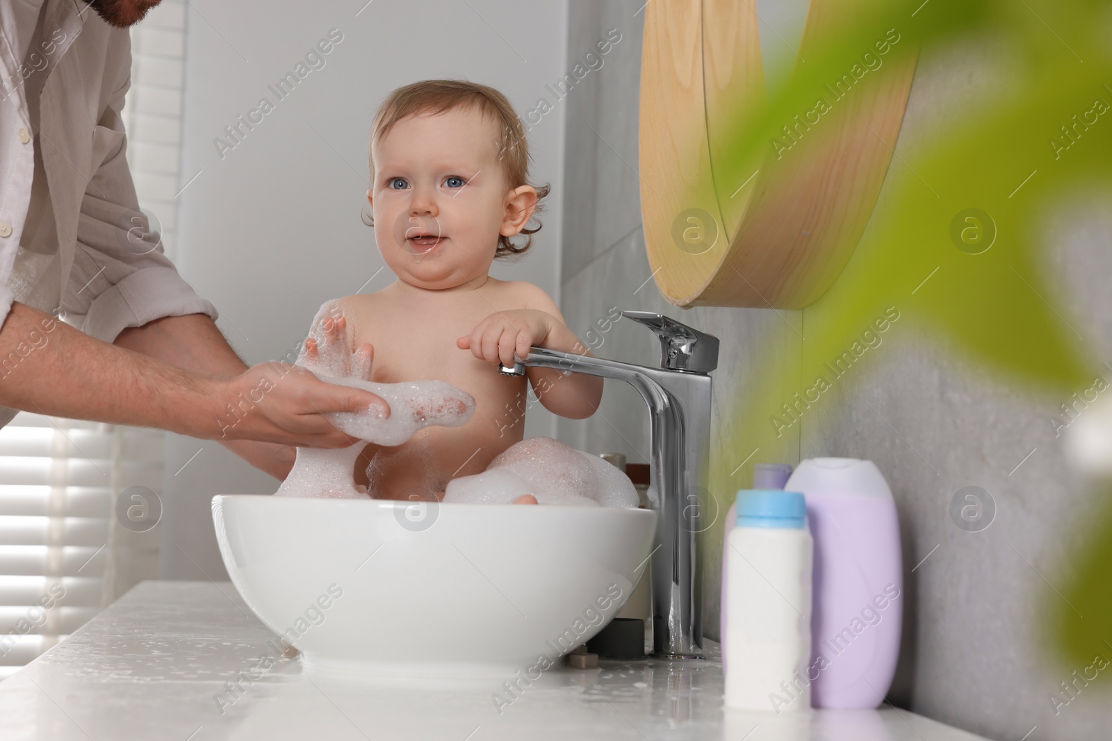 Photo of Father washing his little baby in sink at home