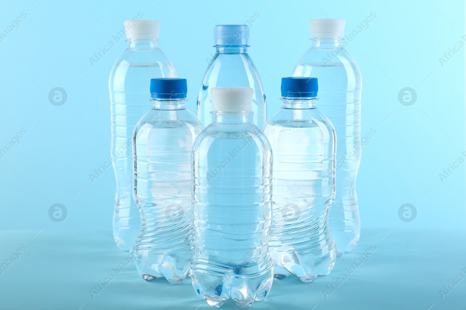 Photo of Set of different plastic bottles with water on blue background