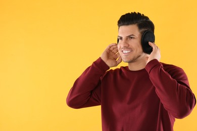 Photo of Man wearing stylish earmuffs on yellow background. Space for text