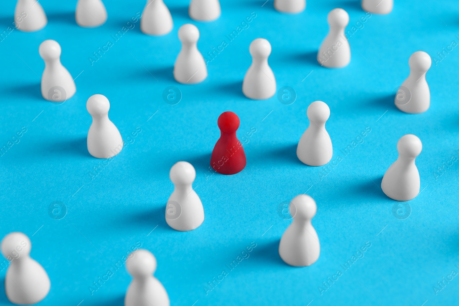 Photo of One red pawn among others on light blue background. Social inclusion concept